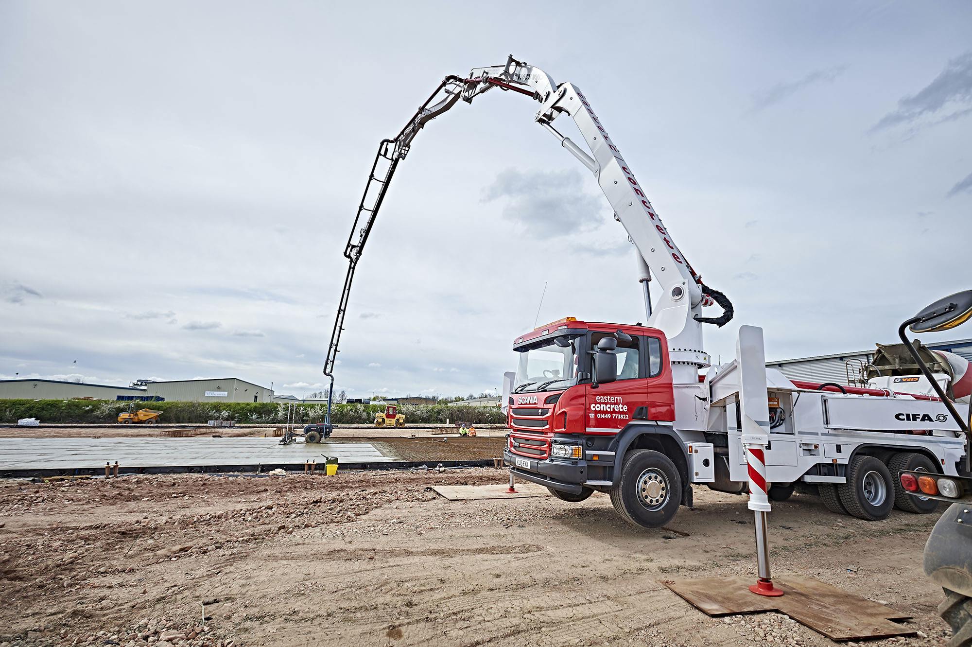 A large concrete pump truck with its boom extended at a construction site.